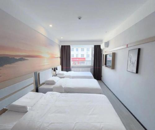 a row of four beds in a room at Junyi Hotel - Zaozhuang High Speed Railway Station in Taozhuang
