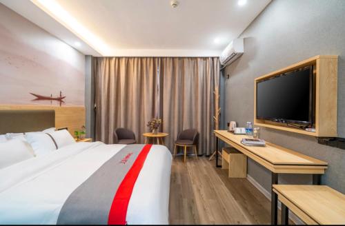 a hotel room with a large bed and a television at Junyi Hotel - Zaozhuang High Speed Railway Station in Taozhuang