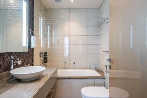 a bathroom with a tub and a toilet and a sink at 2BR Luxurious Damac Paramount Burj Khalifa view Pool, Gym, Bar & Sauna in Dubai