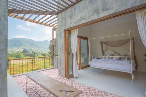 a bedroom with a bed and a balcony with a view at Proud Phu Fah Maerim Resort in Mae Rim