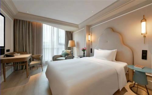 a hotel room with a large white bed and a desk at Mercure Xichang in Xichang