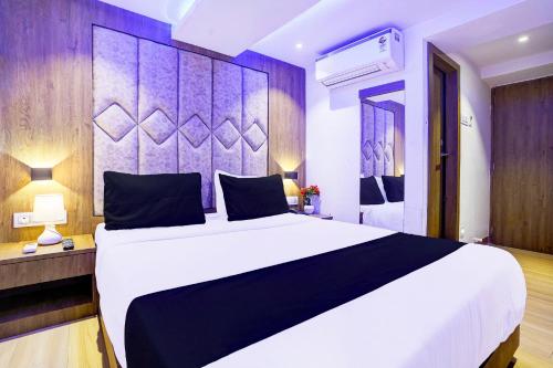 a bedroom with a large white bed and a purple wall at Super Hotel O Sakinaka Andheri Kurla Road in Mumbai
