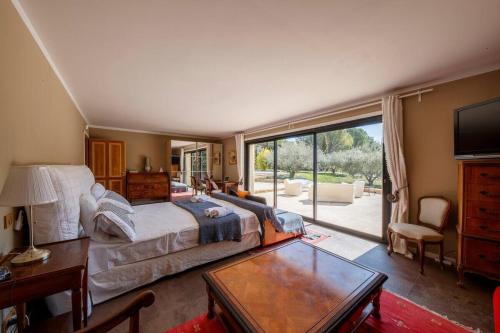 une chambre avec un grand lit et une grande fenêtre dans l'établissement Villa Sérénité, à La Roque-sur-Pernes
