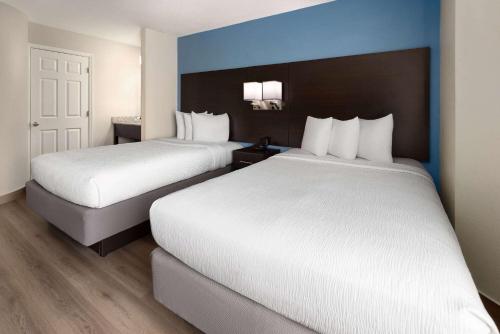 two beds in a hotel room with blue walls at Baymont by Wyndham Newark at University of Delaware in Newark