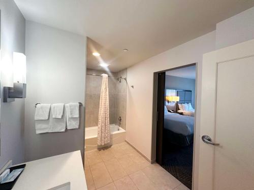 a bathroom with a shower and a bed and a tub at Embassy Suites by Hilton Kansas City Olathe in Olathe