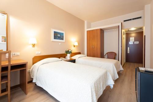 a hotel room with two beds and a desk at Queen Olga Hotel in Thessaloniki