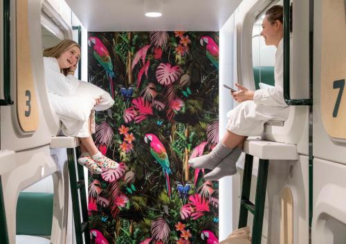two women in an rv with a tropical wallpaper at LyLo Queenstown in Queenstown