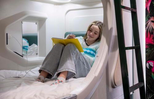 a woman sitting on a bed reading a book at LyLo Queenstown in Queenstown