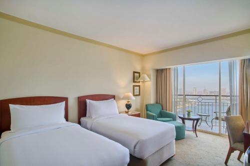 a hotel room with two beds and a balcony at Hilton Cairo Grand Nile in Cairo