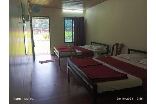 a room with three beds in a room with a window at Cheetah Farms Jungle Stay in Dandeli