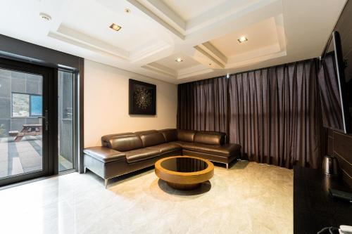 a living room with a leather couch and a table at Browndot Hotel Incheon Songdo in Incheon