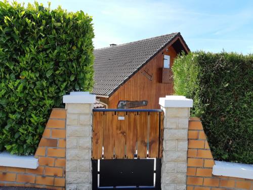a wooden gate in front of a hedge at Gîte de France La petite marmotte in Saint-Béron