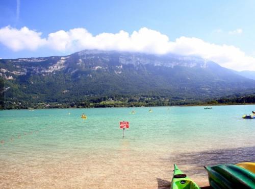 a beach with a sign in the water with a mountain at Gîte de France La petite marmotte in Saint-Béron