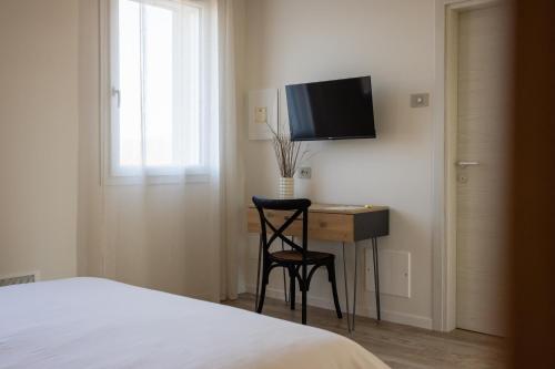 a bedroom with a desk with a chair and a television at Al Casale - Guest House in Sambruson