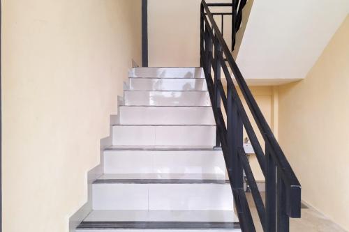a staircase with white stairs and black railings at RedDoorz at Imanuel Homestay Tomohon in Tomohon