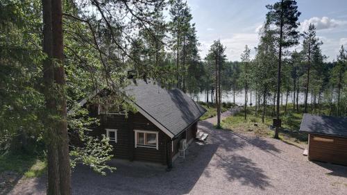a small cabin in the woods next to a lake at Riverside cabin Hiekkaranta in Kuusamo