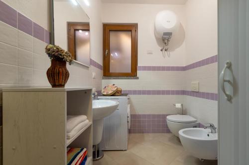 a bathroom with two sinks and a toilet and a mirror at Charlie Beach in Castelsardo