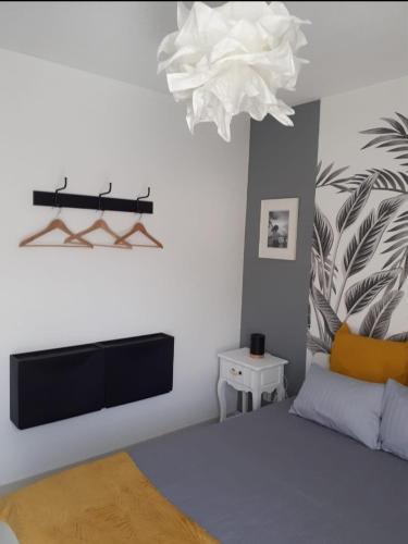 - une chambre avec un lit, une télévision et un lustre dans l'établissement Le Lotus de Jade Bel appartement avec terrasses 2 chambres Résidence avec piscine, à Saint Cyprien Plage
