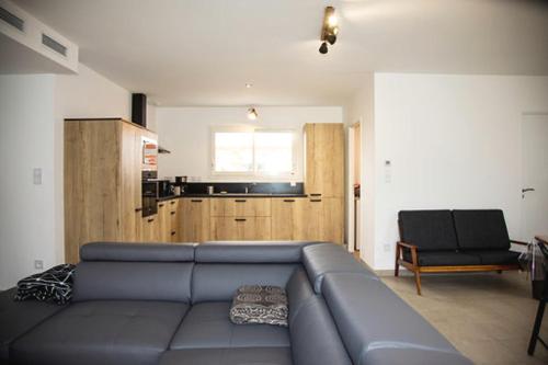 Maison de vacances Moliets et maa في موليات-إي-ما: غرفة معيشة مع أريكة زرقاء وكرسي