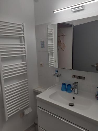 une salle de bain blanche avec un lavabo et un miroir dans l'établissement Le Lotus de Jade Bel appartement avec terrasses 2 chambres Résidence avec piscine, à Saint Cyprien Plage