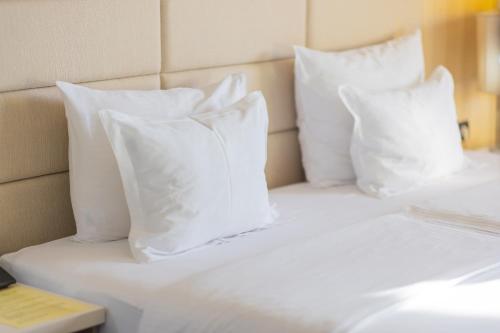 a white bed with four pillows on it at Hotel Holiday in Sarajevo