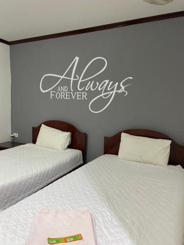a bedroom with two beds and a sign on the wall at DaViKa Hotel in Vientiane