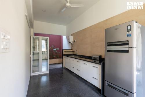 a kitchen with a stainless steel refrigerator and white cabinets at StayVista at Hideaway to Heaven - Lawn & Bonfire in Nashik
