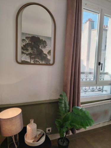 a mirror and a plant in a room with a window at Le Village Montmartre by Hiphophostels in Paris