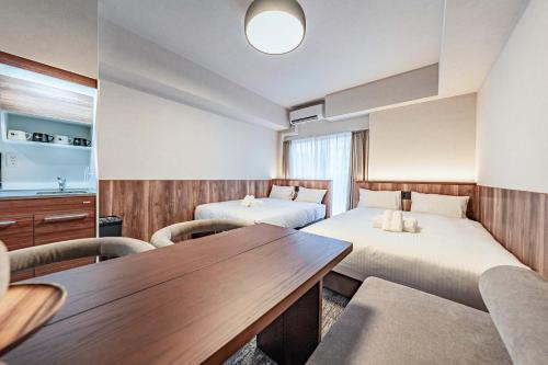 a hotel room with two beds and a table at Apartment Hotel 11 Kuromon 4 in Osaka