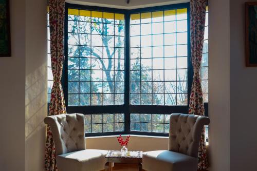 two chairs in front of a large window at Alaya Stays Thistle House - 4 BHK Hideaway with Gazebo & Terrace in Bhīm Tāl