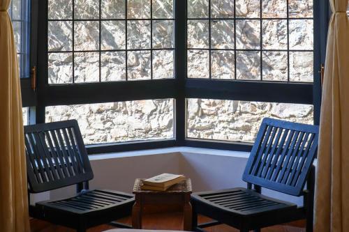 two chairs and a table in front of a window at Alaya Stays Thistle House - 4 BHK Hideaway with Gazebo & Terrace in Bhīm Tāl