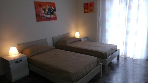 2 camas en una habitación pequeña con 2 lámparas en La Casetta al 21, en Matera