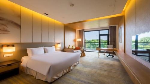 a bedroom with a large white bed and a desk at Holiday Inn Kunshan Huaqiao by IHG in Kunshan