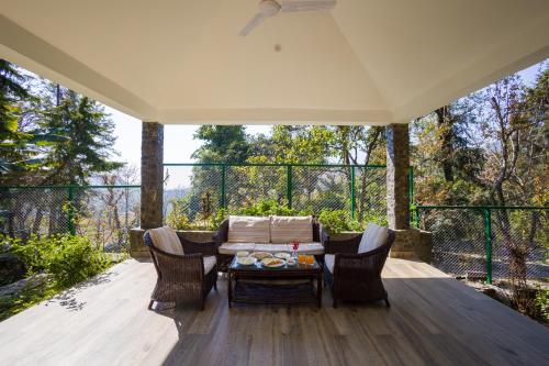 a patio with a couch and chairs on a deck at Alaya Stays Thistle House - 4 BHK Hideaway with Gazebo & Terrace in Bhīm Tāl
