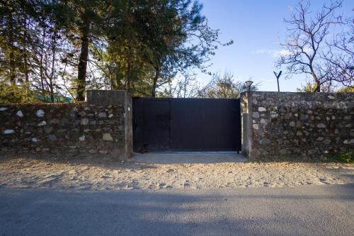 a gate in a stone wall next to a fence at Alaya Stays Thistle House - 4 BHK Hideaway with Gazebo & Terrace in Bhīm Tāl
