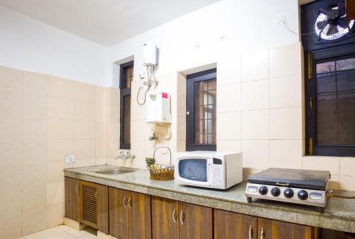 a kitchen with a sink and a microwave on a counter at Alaya Stays Thistle House - 4 BHK Hideaway with Gazebo & Terrace in Bhīm Tāl