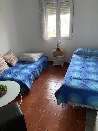 a room with two beds and a table and a window at Habitación luminosa en piso compartido in Mairena del Aljarafe