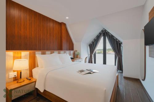 a bedroom with a large white bed and a window at Nature Hotel - Nam Ky Khoi Nghia in Da Lat