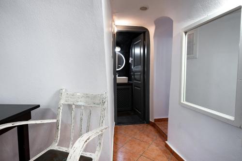a white chair sitting in a hallway with a black door at Lotza Studios in Oia