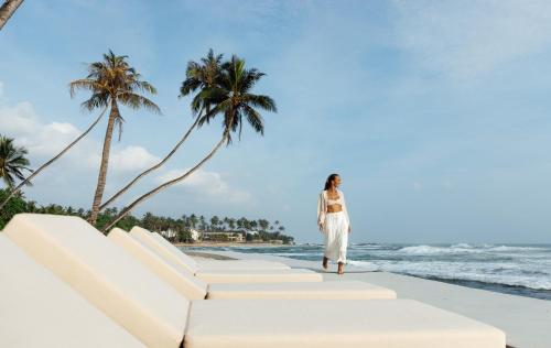 a woman in a white dress standing on the beach at Radisson Collection Resort Galle in Galle