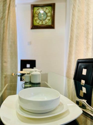 a plate on a table with a clock on the wall at Silverstone Apartments Nairobi, Kilimani in Nairobi