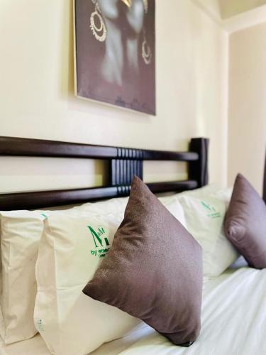 a bed with several pillows on top of it at Silverstone Apartments Nairobi, Kilimani in Nairobi