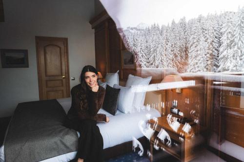 a woman sitting on a bed in a room at Hotel Carlina in Courchevel