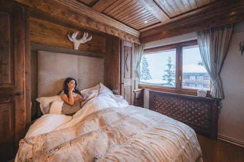 a woman sitting on a bed in a bedroom at Hotel Carlina in Courchevel