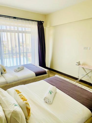 a hotel room with two beds and a window at Silverstone Apartments Nairobi, Kilimani in Nairobi
