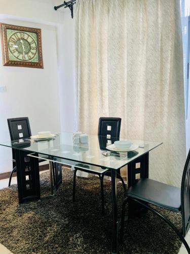 a glass table with chairs and a clock on the wall at Silverstone Apartments Nairobi, Kilimani in Nairobi