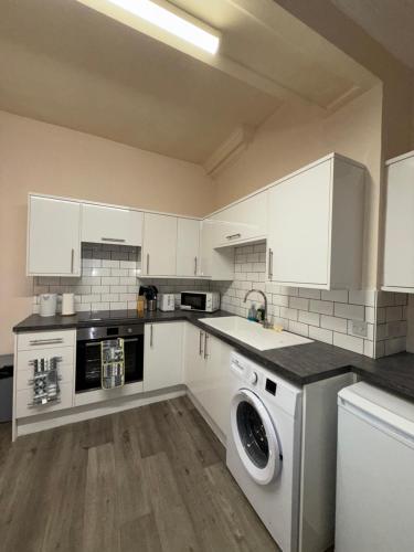 a kitchen with white cabinets and a washing machine at Luxe city stay in Ipswich