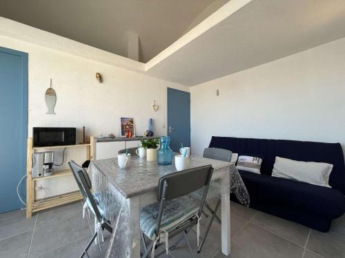 un salon avec une table et un canapé bleu dans l'établissement Appartement 1 pièce - Gruissan GN140-1033, à Gruissan