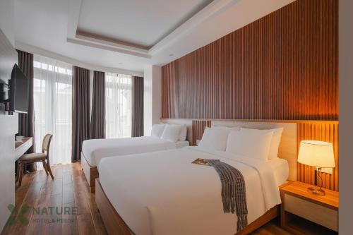 a hotel room with two beds and a desk at Nature Hotel - Nam Ky Khoi Nghia in Da Lat