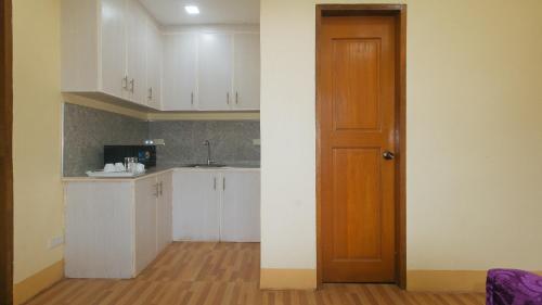 a kitchen with white cabinets and a wooden door at RedDoorz at Casa Barcelona Condotel in Iloilo City